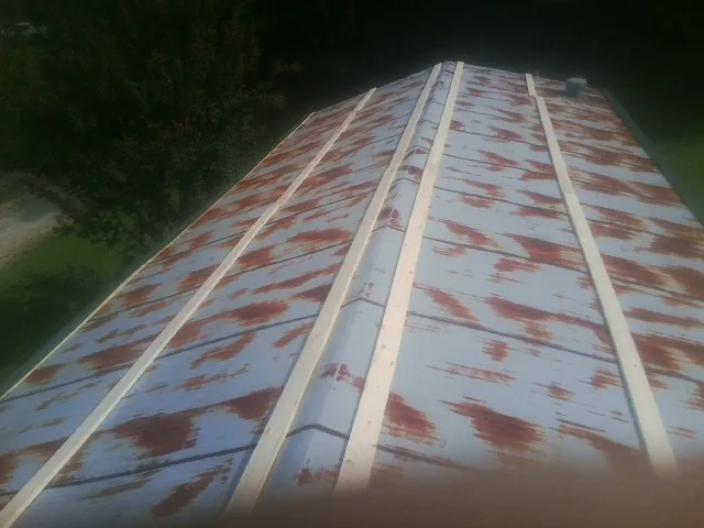 Rusted metal roof panels with new wood purlins before replacement in Varysburg