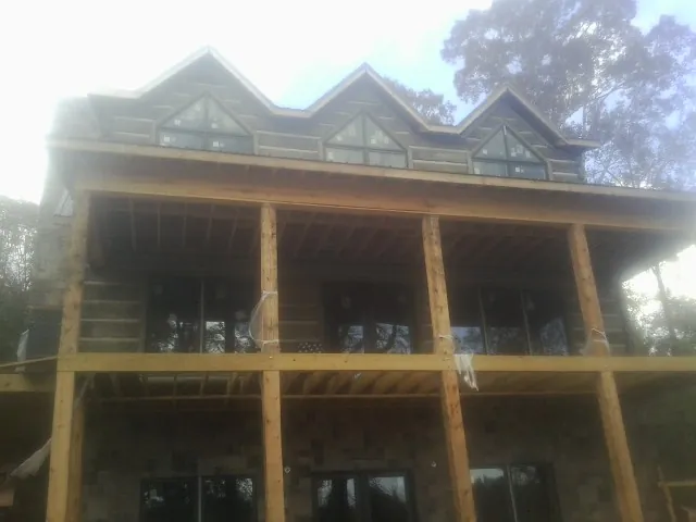 Dormers and porch framing on a large log home under construction — Roof Coating work by our crew in Varysburg
