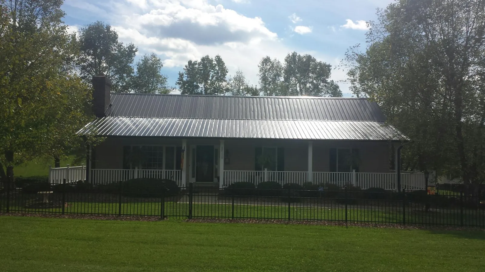 Gray metal roof on a brick ranch with a full width front porch — Gutter Guard Installation work by our crew in Varysburg