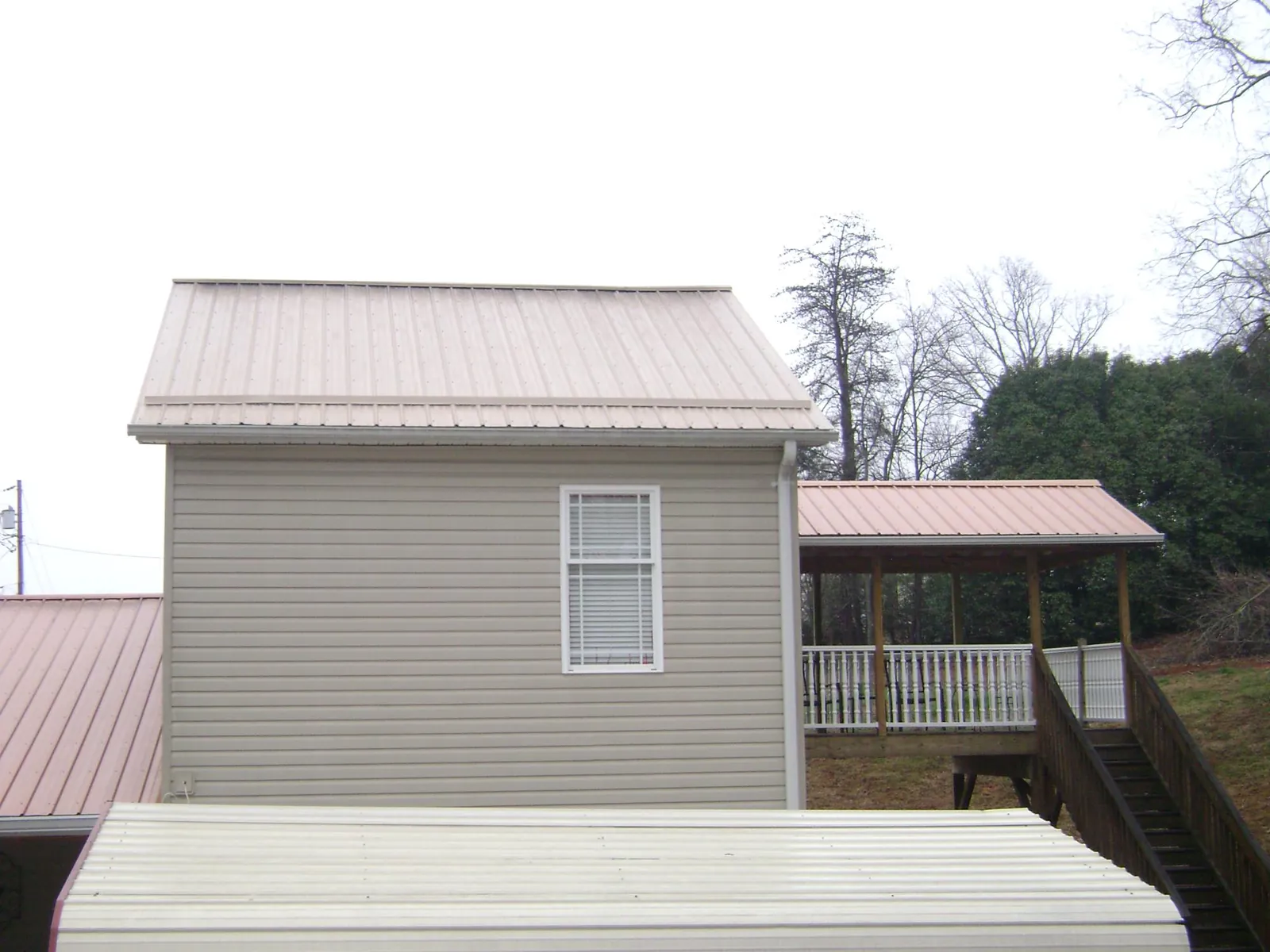 Tan metal roofs on a two story addition and attached porch, from a Roof Replacement job in Varysburg