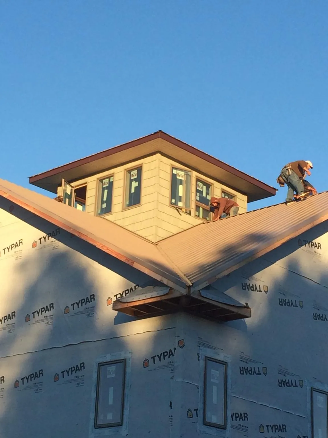 Roofers working around a rooftop cupola on a new metal roof at sunset — Roof Waterproofing in Varysburg by Roofing Brothers
